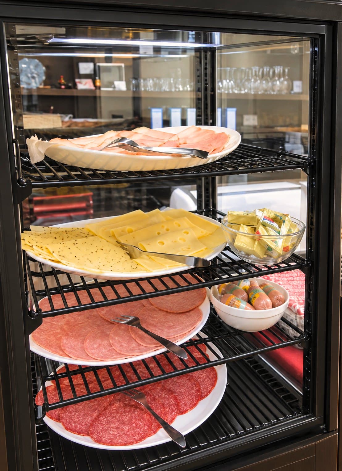 Koelvitrine bij het ontbijtbuffet met vleeswaren en kaas